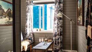 A cozy room with a window, a table with glasses and a candle, and a floor lamp. - Fjærland Fjordstove Hotell (Sogndal)