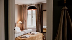A hotel room with a bed, a lamp, a window with curtains, and a hanging light fixture. - Fjærland Fjordstove Hotell (Sogndal)