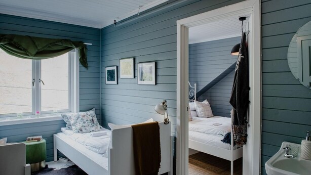 Un dormitorio con dos camas, una ventana con cortinas, una mesita de noche, un espejo y un lavamanos.