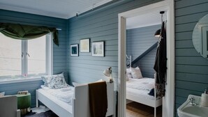 A bedroom with two beds, a window with curtains, a bedside table, a mirror, and a sink. - Fjærland Fjordstove Hotell (Sogndal)
