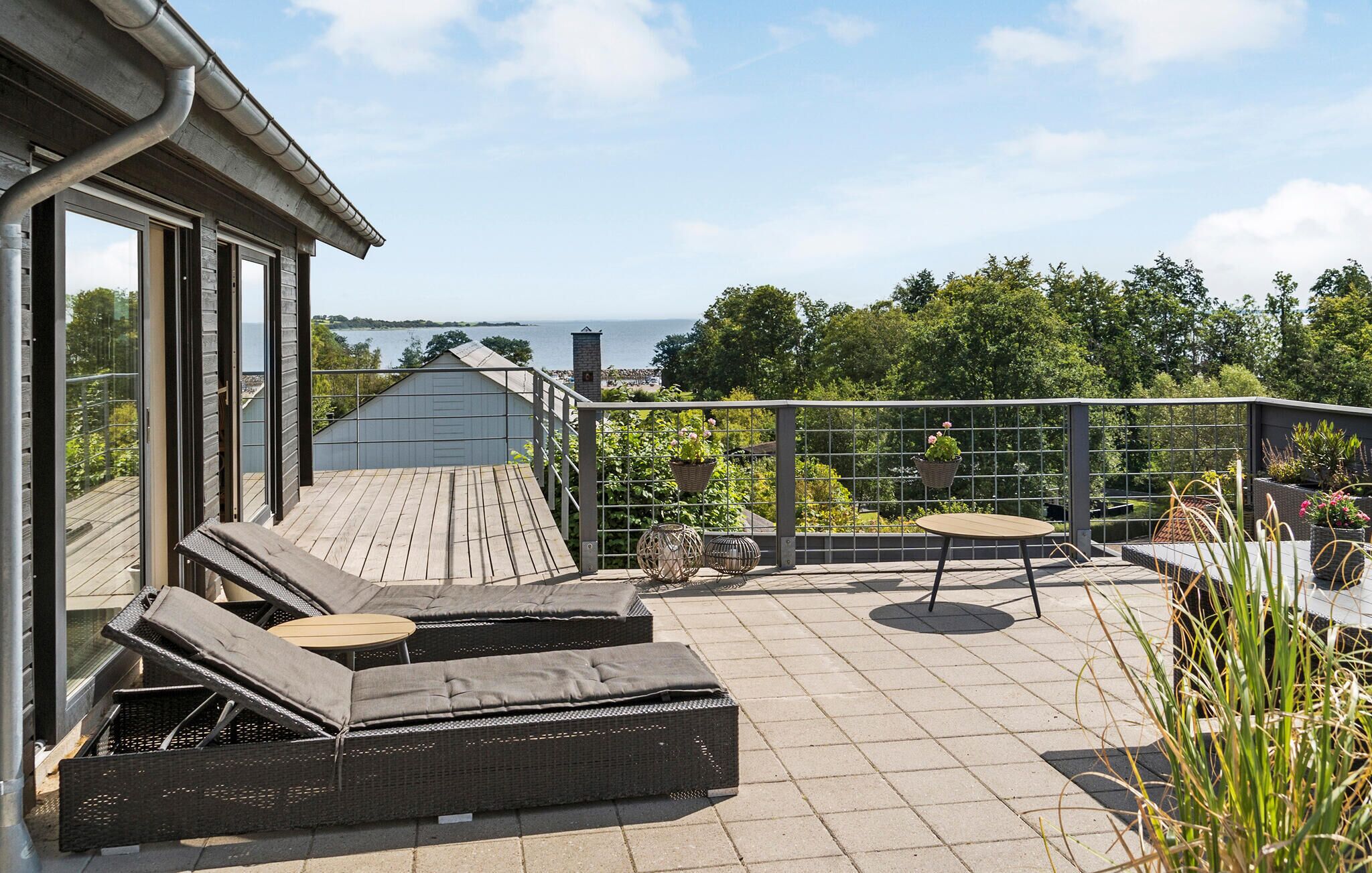 A rooftop patio with wicker furniture, a small table, and hanging planters.