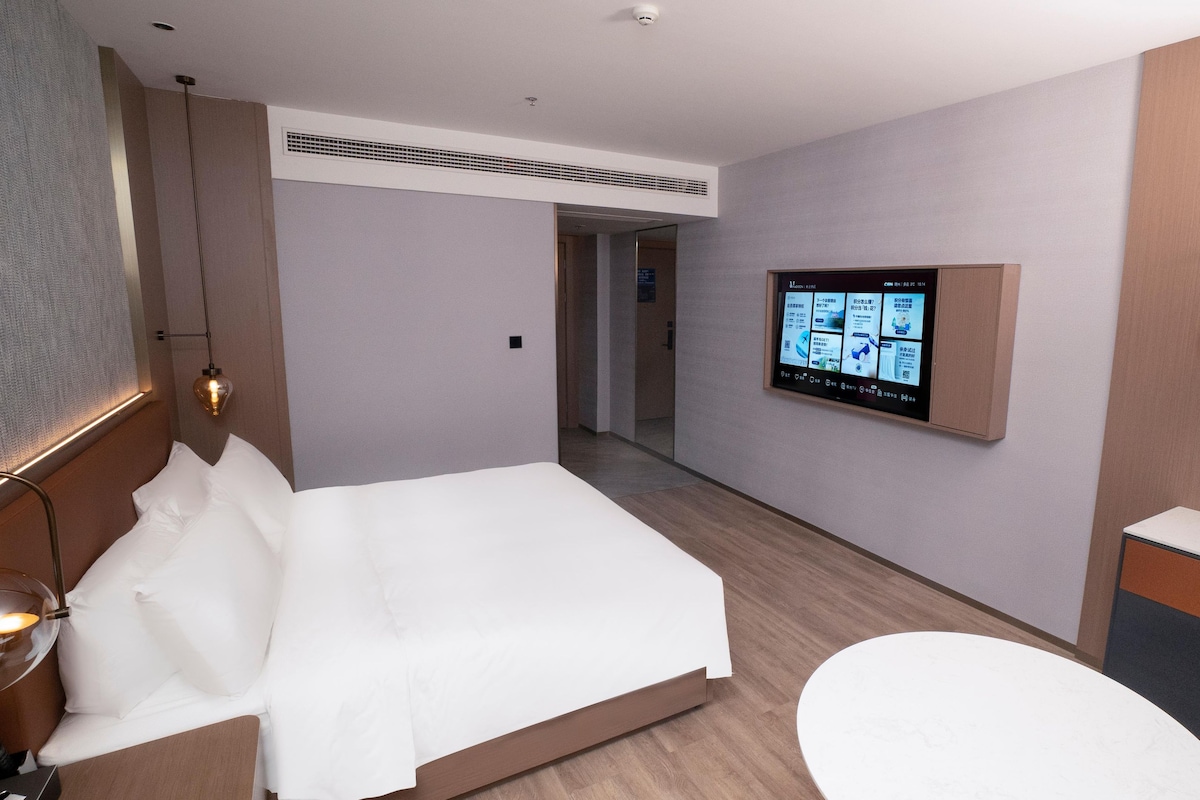 Hotellihuone, jossa on sänky, työpöytä, televisio ja kylpyhuone.