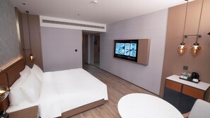 Hotellihuone, jossa on sänky, työpöytä, televisio ja kylpyhuone.