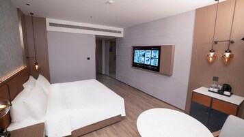 Una habitación de hotel con cama, escritorio, televisor y baño.