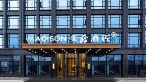 A modern hotel entrance with a prominent sign reading "MADISON 美都酒店".