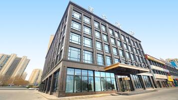 A modern hotel building with multiple floors, large windows, and a prominent entrance.