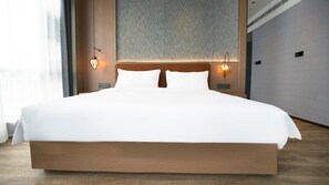 A large bed with a wooden frame, two wall-mounted light fixtures, and a textured wall behind the bed.
