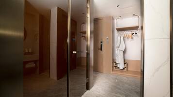 A modern bathroom with a shower, a towel rack, and a mirror.