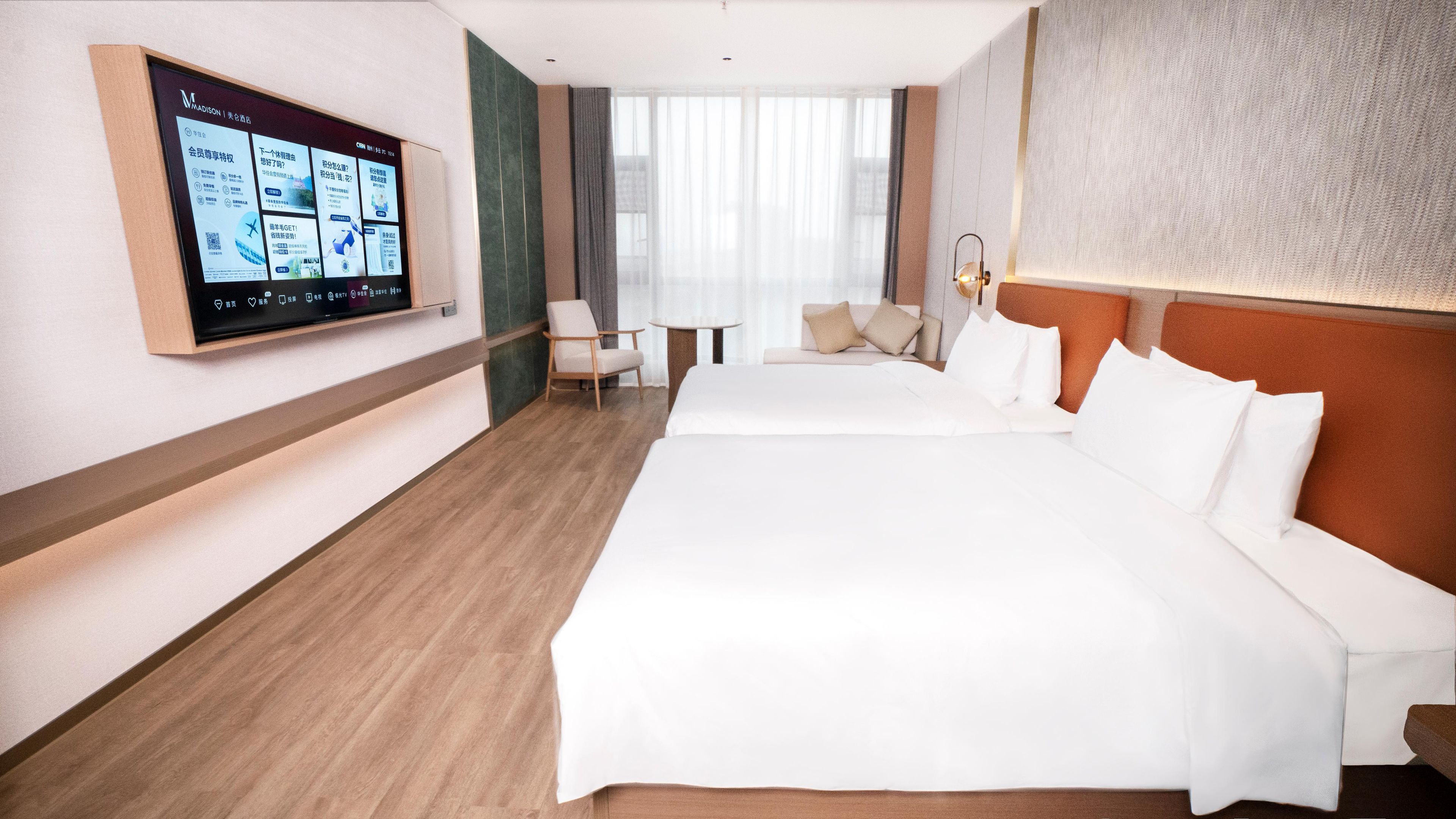 A hotel room with a large bed, a desk, a chair, and a television mounted on the wall.