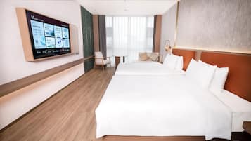 A hotel room with a large bed, a desk, a chair, and a television mounted on the wall.