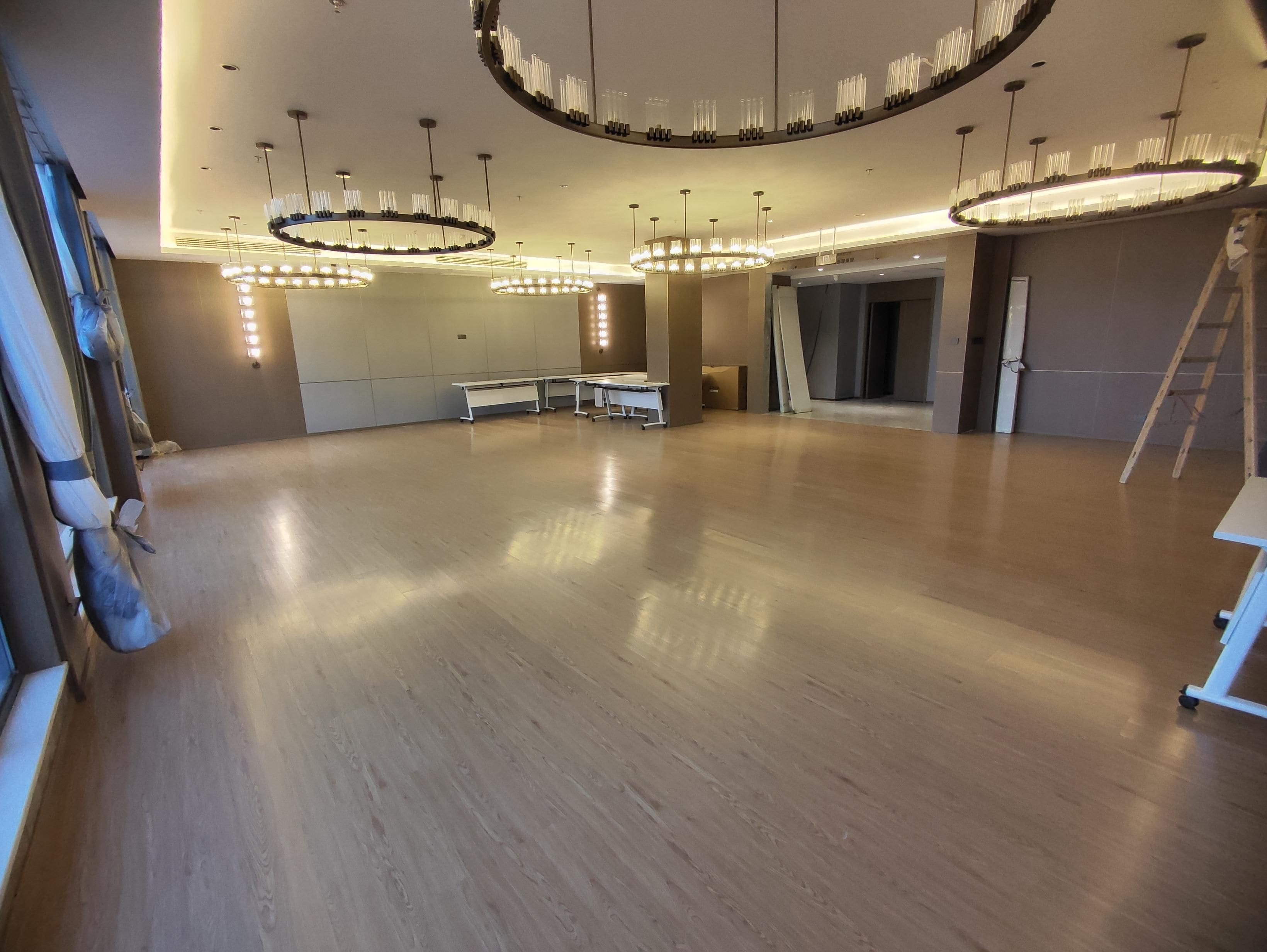 Una habitación amplia con piso de madera pulida, varias mesas y un espejo grande.