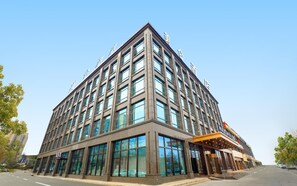 Un hôtel moderne doté d’une grande façade en verre, de plusieurs étages et d’une entrée imposante avec un espace abrité.