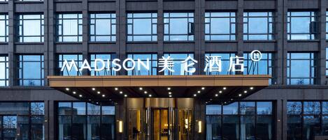 A modern hotel entrance with a prominent sign reading "MADISON 美都酒店".