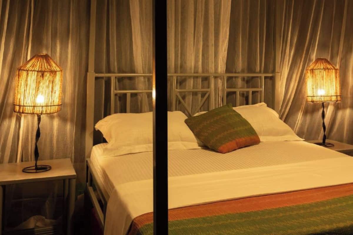 Une chambre d’hôtel avec un lit, deux lampes de chevet et une fenêtre avec des rideaux.