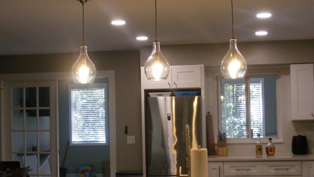 A kitchen with a large island, stainless steel refrigerator, and pendant lighting. - Modern Seaside Beach Retreat (Saint Helena Island)