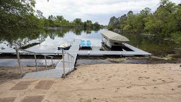 Un muelle con un bote, un vehículo cubierto y una zona arenosa.