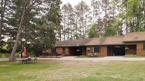 A log cabin with a covered patio, outdoor seating, and a grassy area. - Cozy 1BR 1BA Cabin #4 Riverside Point Resort (Park Rapids)