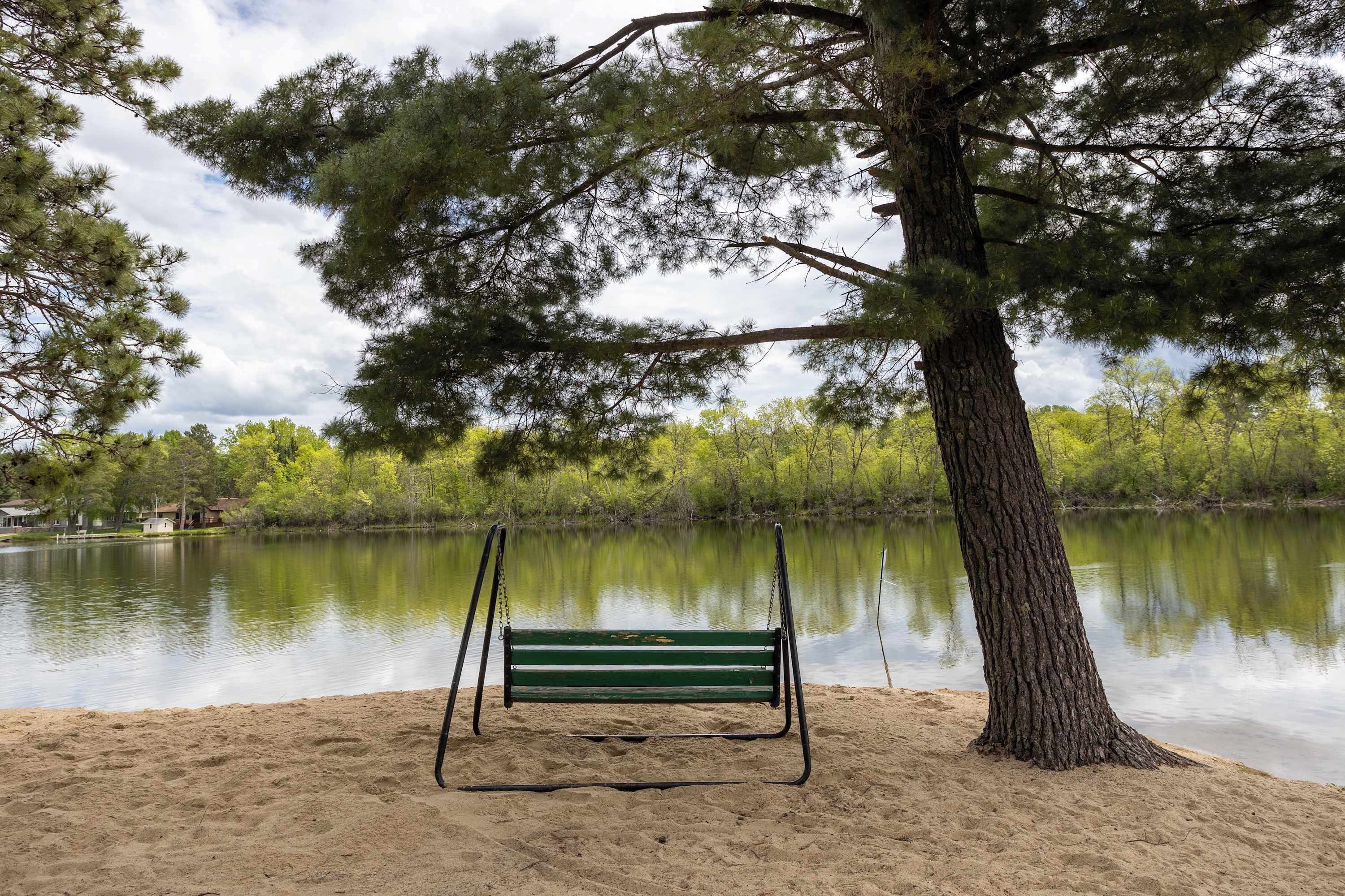 Eine Bank am See, im Hintergrund Bäume.