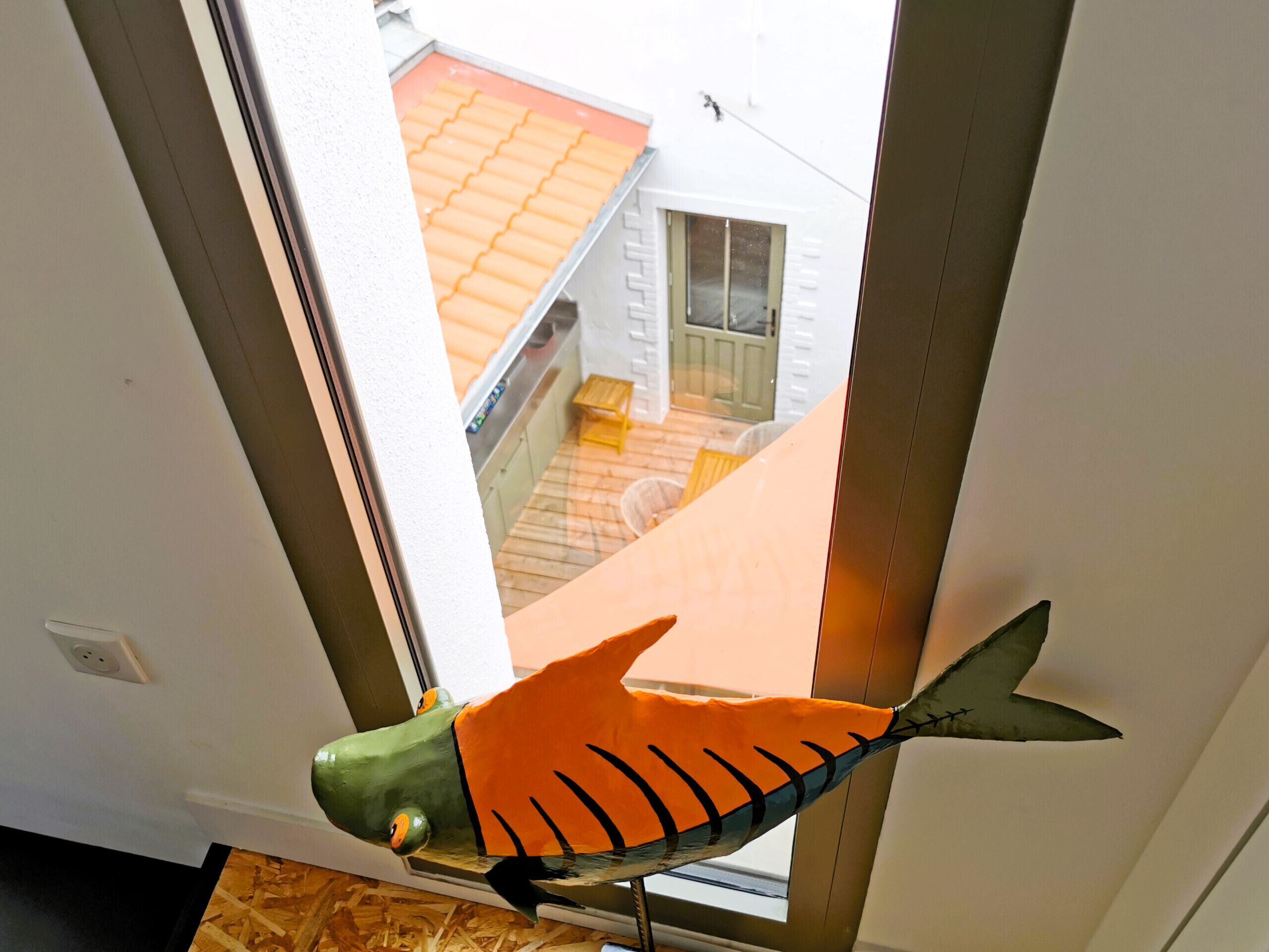 A fish-shaped decoration hanging near a window.