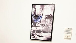 Zona pranzo con tavolo apparecchiato per due, una cornice sopra e un termostato al muro.