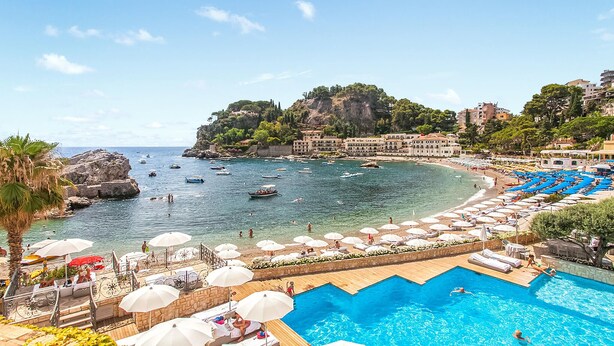 A resort with a swimming pool, beach, and boats.