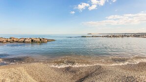 A pebbled beach with calm waters and a clear sky.