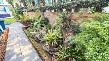 A garden with a stone pathway, various potted plants, and a brick wall.