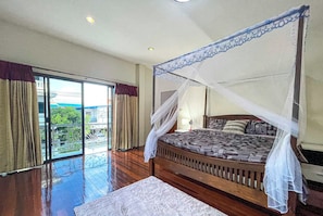 Une chambre à coucher avec un lit à baldaquin, une grande fenêtre avec des rideaux et une vue sur la verdure.