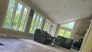 Un salon spacieux doté d’un sol en pierre, de grandes fenêtres et d’une cheminée.