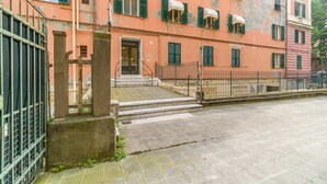 A building with a pink facade, green shutters, and a metal gate. - GuestHost - Genova Brignole Modern and Central Apartment (Genova)