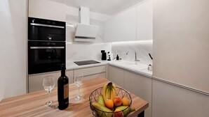 A modern kitchen with a built-in oven, a coffee maker, and a fruit bowl on the counter. - 1 bedroom beautiful apartment in Muntic (Muntic)