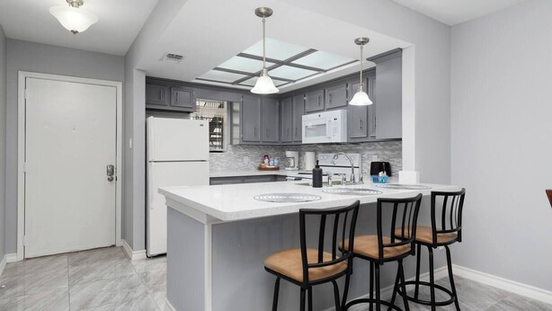 A modern kitchen with a central island, bar stools, and a skylight. - The 3 Queen Modern by 802 & Paredes (Brownsville)
