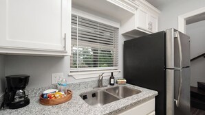 Eine Küche mit Granit Arbeitsplatte, Spüle aus Edelstahl und einem schwarzen Kühlschrank.