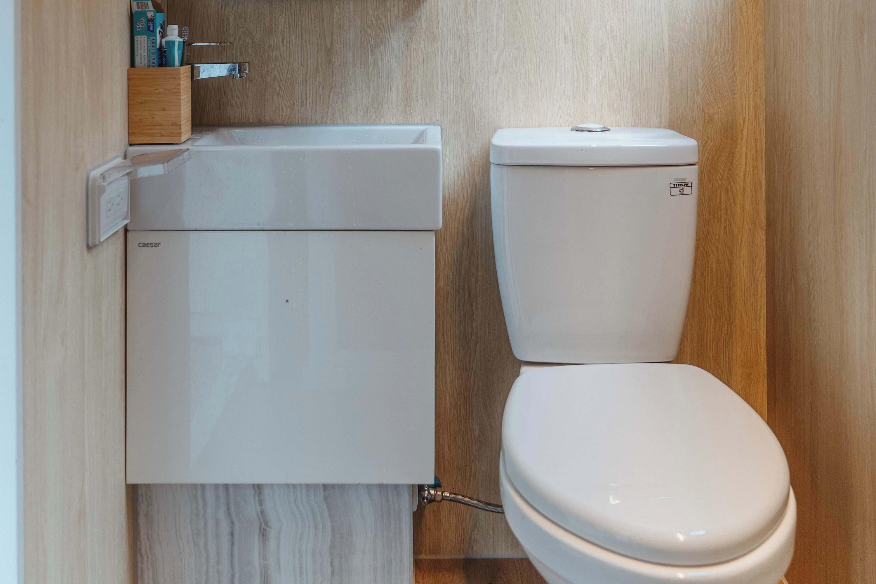 Une petite salle de bain avec des toilettes blanches et un meuble blanc portant l’inscription « Caesar ».