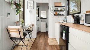 A compact kitchen with white cabinetry, a wooden countertop, and a black refrigerator. - Charmingly Tiny by Tiny Away (Springmount)