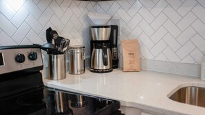 Une cuisine équipée d’une machine à café, d’une bouilloire, d’un paquet de café et d’un évier.