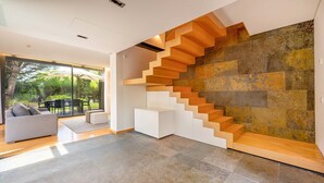 A modern interior with a unique staircase, a glass door leading to an outdoor area, and a minimalist living space.
