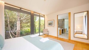 A modern bedroom with a large bed, a chair, and a mirror.