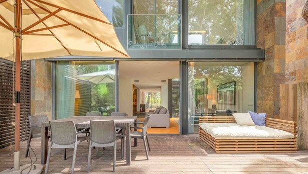 A modern outdoor patio with a dining table, chairs, and a large umbrella.