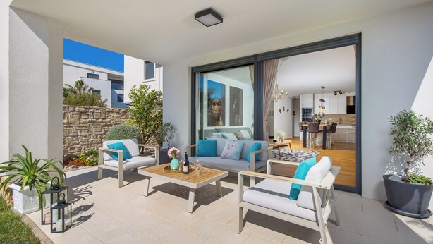 Un espace de vie extérieur moderne comprenant un canapé, des fauteuils et une table basse.