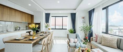 Una cocina moderna con armarios de madera, un comedor con una mesa grande y una zona de estar acogedora con un sofá y una ventana con vistas a la ciudad.