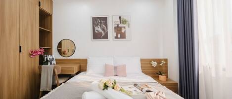 Un dormitorio moderno con una cama grande, un armario de madera, mesitas de noche y decoración en la pared.