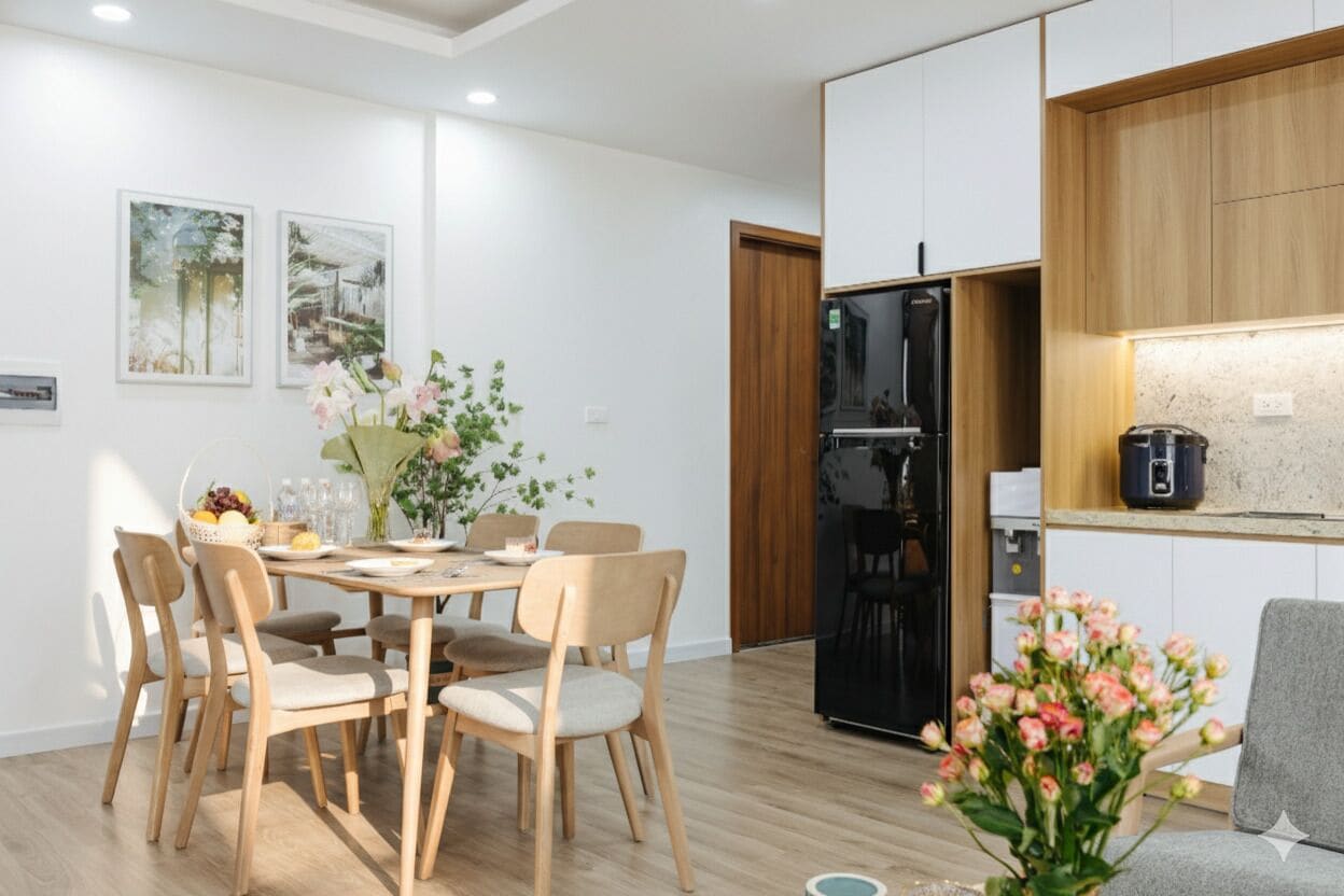 A modern kitchen with a black refrigerator, wooden cabinets, and a dining area with a table and chairs.