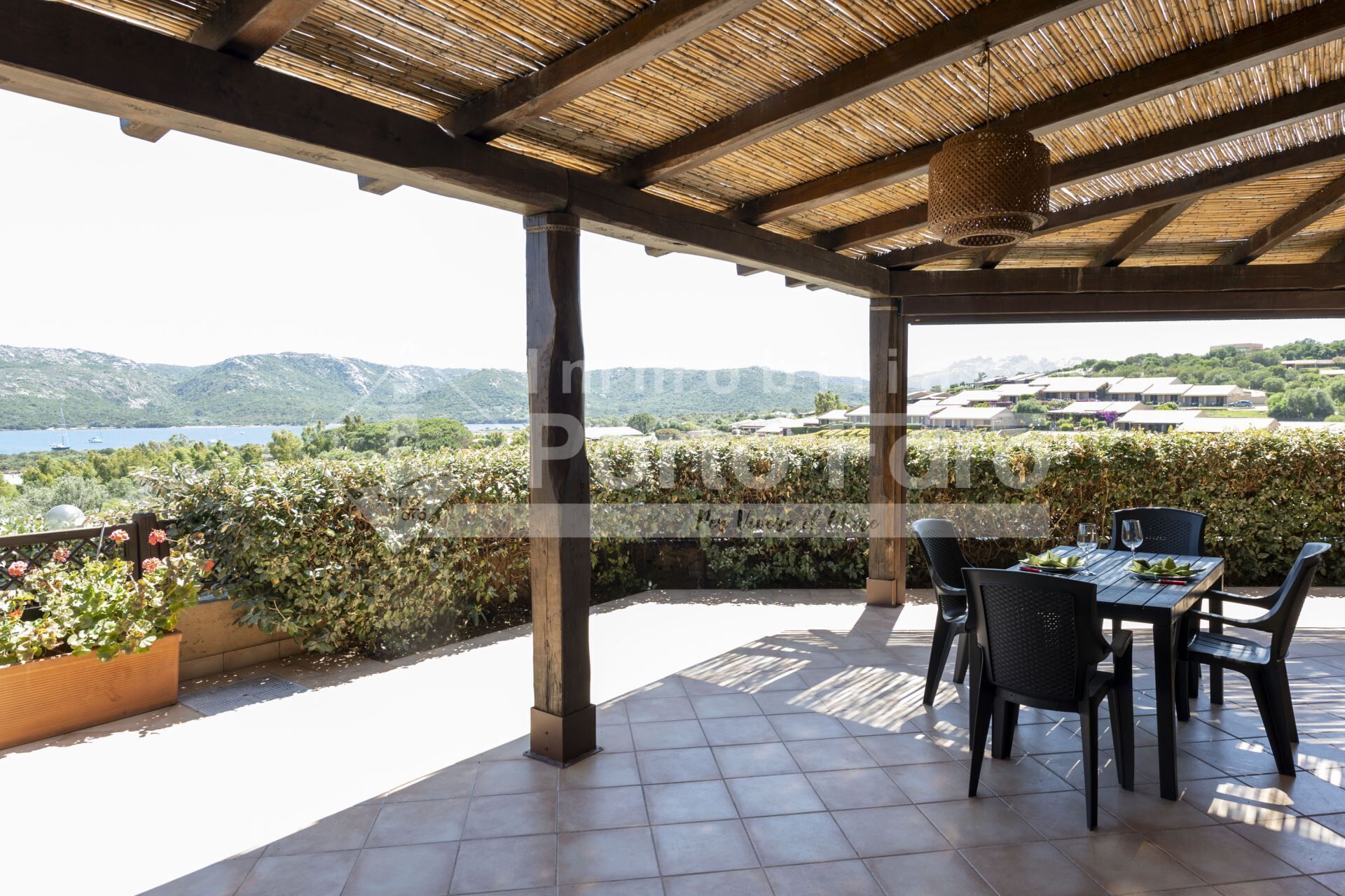 A covered outdoor seating area with a view of a lake and hills.