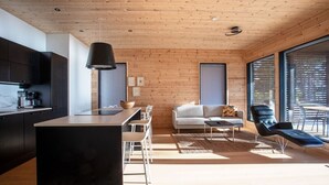 Une cuisine moderne avec des meubles de couleur sombre, un îlot central et un luminaire suspendu.
