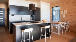 Une cuisine moderne dotée d’un îlot central, de tabourets de bar et d’une table à manger avec des chaises.