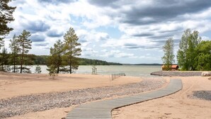 Une plage de sable avec une promenade en bois qui mène à une petite cabane au bord de l’eau.