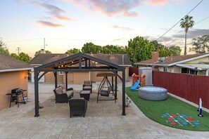 A backyard with a covered patio, outdoor seating, a swing set, a slide, and a small play area. - Coastal Home Near UCSB & Airport + Hot Tub, King Beds, Fast Wifi, Sleeps 6 (Goleta)