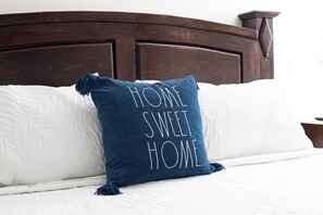 A bed with a dark wooden headboard, a white comforter, and a blue pillow with the text "HOME SWEET HOME." - Coastal Home Near UCSB & Airport + Hot Tub, King Beds, Fast Wifi, Sleeps 6 (Goleta)