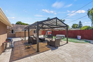 A covered patio area with outdoor furniture, a grill, and a children's play area. - Coastal Home Near UCSB & Airport + Hot Tub, King Beds, Fast Wifi, Sleeps 6 (Goleta)
